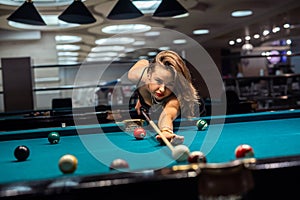 female player playing pool and aiming the billiard ball with cue