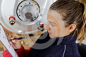 female plumber checking boiler