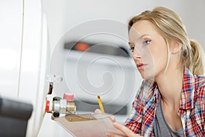 female plumber with clipboard looking at boiler