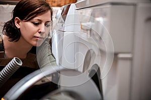 female plumber examines or repairs a washing machine or washer