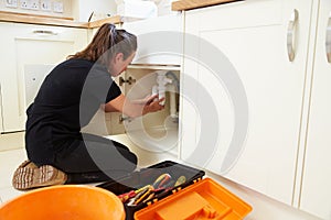 Female plumber fixing a kitchen sink