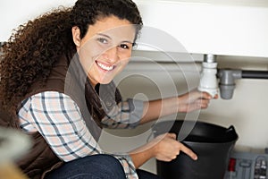 female plumber fixing sink in kitchen