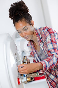 female plumber servicing central heating boiler