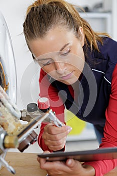 Female plumber using tablet while working on boiler