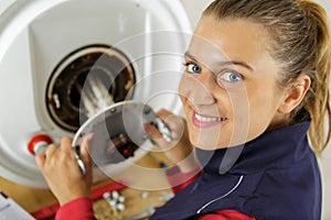 female plumber working on central heating boiler