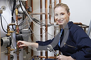 Female Plumber Working On Central Heating Boiler