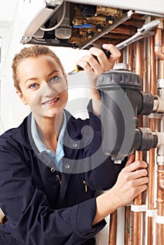 Female Plumber Working On Central Heating Boiler