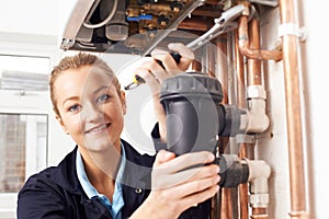 Female Plumber Working On Central Heating Boiler