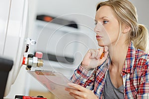 Female plumber working on central heating boiler