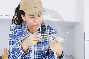 Female plumber working on sink using wrench