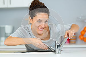 Female plumber working on sink using wrench