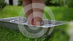 Female plus-size legs stepping into water in tub in slow motion outdoors. Unrecognizable overweight Caucasian lady