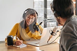 Female podcaster in headphones interviewing man guest in studio