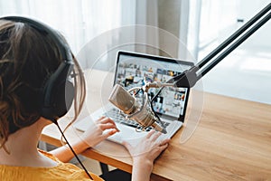 Female podcaster recording her podcast using microphone and laptop at his home broadcast studio