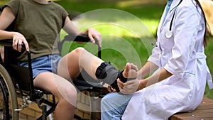 Female podiatric physician examining injured patient leg, ankle supporting brace photo