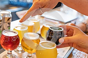 Female Pointing to Glass of Micro Brew Beer From Variety