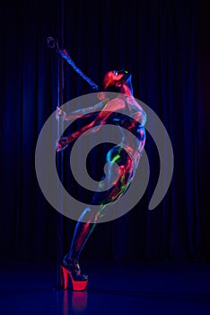 Female pole dancer in bright neon colours under ultraviolet