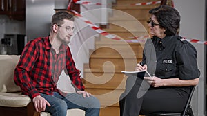 Female police officer collects testimony of male robbery victim. Serious Caucasian woman in sunglasses and uniform