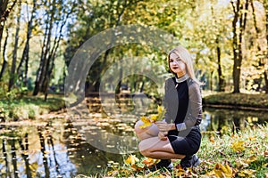 Female porteait in autumn park. Beaurtiful woman in black dress posing with yellow trees