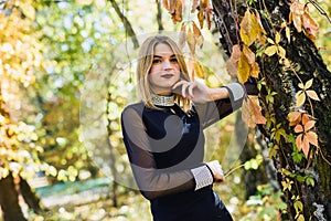 Female porteait in autumn park. Beaurtiful woman in black dress posing with yellow trees