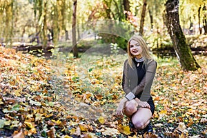 Female porteait in autumn park. Beaurtiful woman in black dress posing with yellow trees