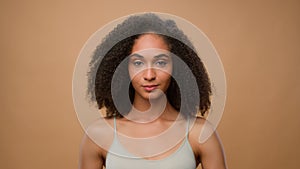 Female portrait in beige studio background attractive African American woman holding fresh avocado near face healthcare