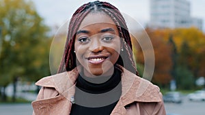 Female portrait close-up young satisfied happy african american woman standing in autumn park looking at camera smiling