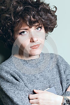 Female portrait of a curly-haired beautiful girl in a knitted woolen sweater