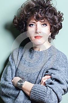 Female portrait of a curly-haired beautiful girl in a knitted woolen sweater