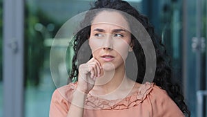 Female portrait hispanic woman curly pensive girl ethnic model lady deep in thought thinks makes decision pondering plan