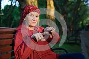 Female portrait of mature woman dressed in red clothes and showing two fingers sitting on the bench and enjoying a good