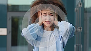 Female portrait outdoors sad stress african american girl young upset desperate woman with curly hair covering ears with