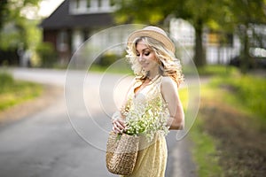 Female portrait outdoors. a woman in a straw hat in a flower field with a bouquet of wild flowers. Summer in the country