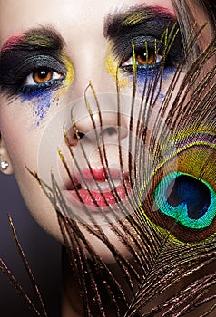 Female portrait with peacock feather on foreground and beauty face makeup