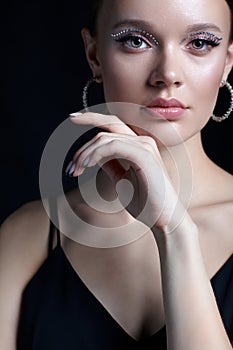 Female portrait with rhinestones makeup. Woman with earring in the form of a shiny ring in the ear