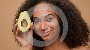 Female portrait studio background smiling African American woman holding fresh healthy avocado face beauty skin care