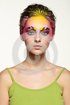 Female portrait with unusual face art make-up. Paint on brows, hair and around eyes