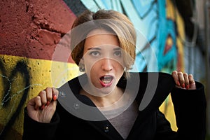 Female portrait of young girl with short blonde hair near the wall with graffiti. Youth culture, street art concept