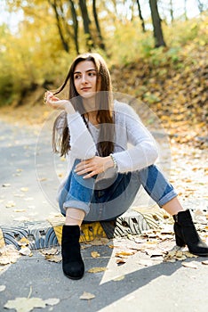 Female portrait. Young woman in casual wear posing in autumn forest with yellow leaves