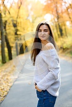 Female portrait. Young woman in casual wear posing in autumn forest with yellow leaves