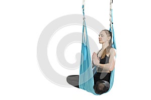 Female posing aerial anti-gravity yoga on hammock. Girl sits in lotus position in blue hammock on white background