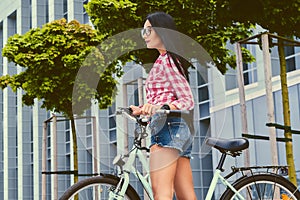 Female posing on a bicycle over modern building background.