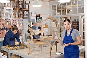 Female positive restorer restores the wooden frame of an antique chair