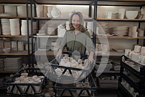 Female potter holding cups in crate