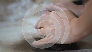 Female potter kneads brown clay at her workplace.