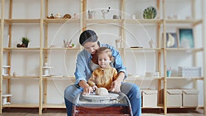 Female potter makes a pot on the pottery wheel with her daughter