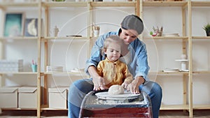 Female potter makes a pot on the pottery wheel with her daughter