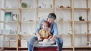 Female potter makes a pot on the pottery wheel with her daughter