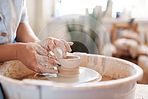 Female potter making a pot on pottery wheel