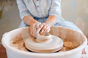 Female potter making a pot on pottery wheel